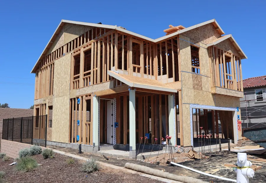 A two-storey house frame fully sheathed in oriented strand board, with window and door openings cut but unglazed